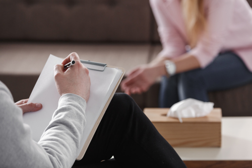 a man with a clipboard giving a counselling session to a female client